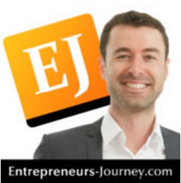 A man in a suit and tie is standing in front of the ej logo.