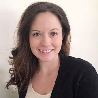 A woman wearing a black cardigan smiles for the camera.