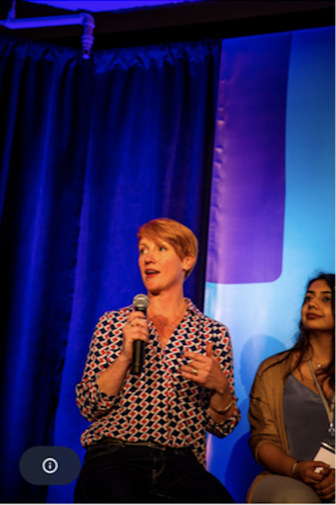 Two women sitting on stage with microphones in front of them.
