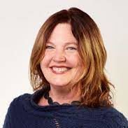 A woman in a blue sweater smiles for the camera.