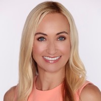 A woman in a pink top with long blonde hair.