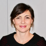 A woman wearing a black sweater and red lipstick.