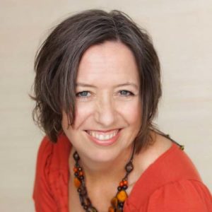 A smiling woman in an orange top.