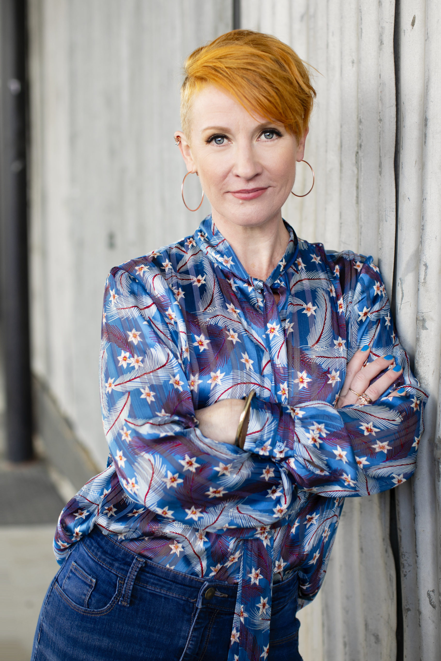 Belinda Weaver leans against a wall with her arms crossed