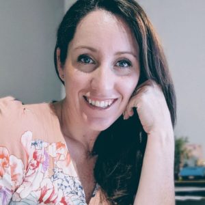 A woman smiles while sitting in front of a computer.