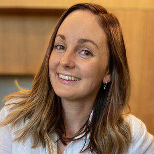 A woman in a white shirt smiles for the camera.