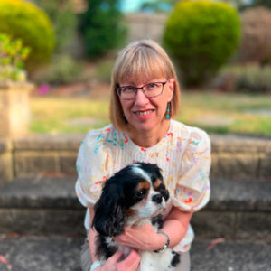 Copywriter, Kerstin Sheppard, sits with glasses and a black and white dog.