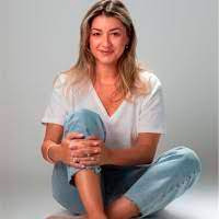 A woman sitting on the floor in a white shirt and jeans.