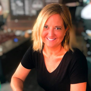 A woman in a black shirt smiling at a table.