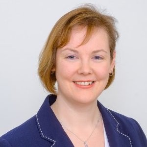 A woman in a blue blazer smiling.