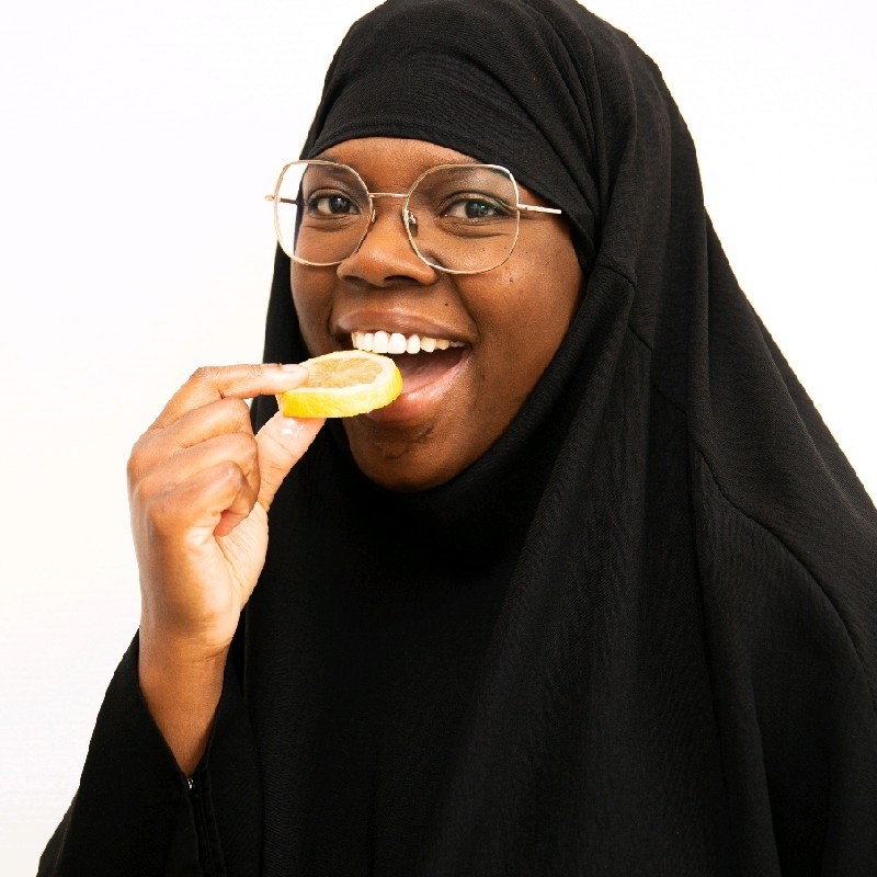 A woman wearing a hijab eating an orange.