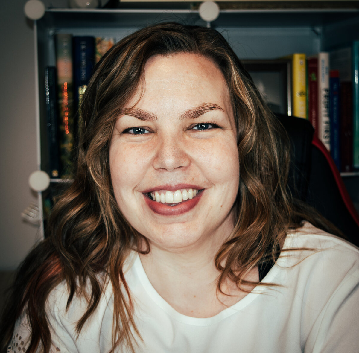 A woman smiling in front of a book shelf.
