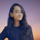 A girl with long hair standing in front of a sunset.