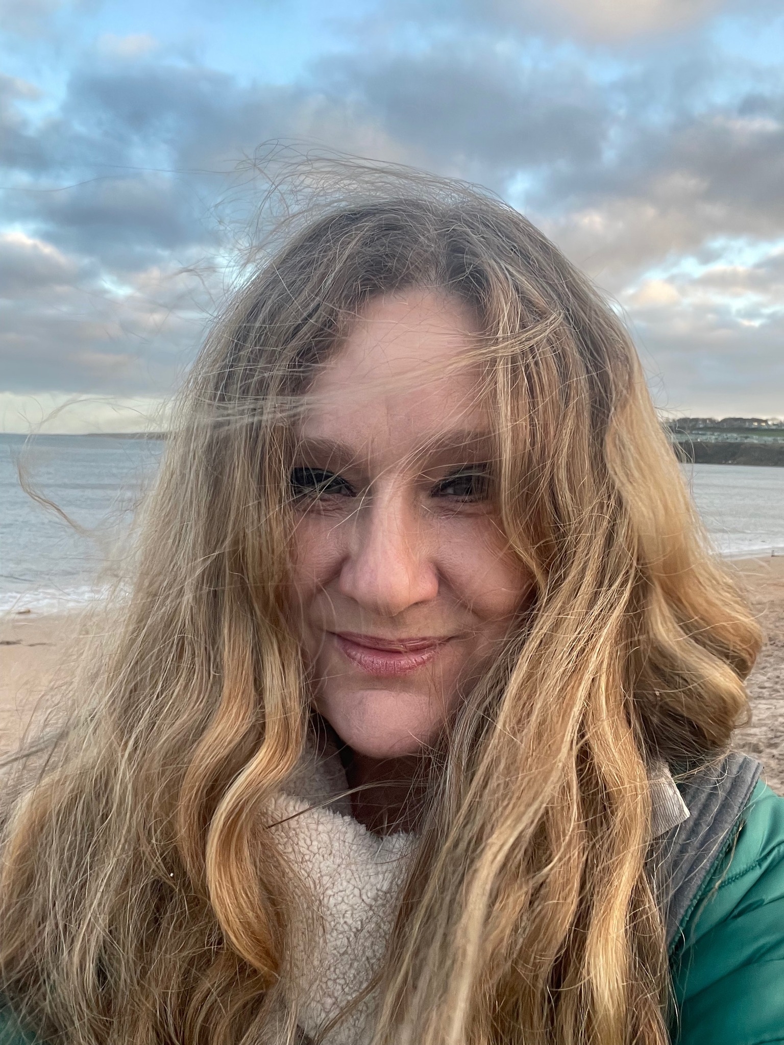 Copywriter, Lisa McKnight, with long hair standing on the beach.