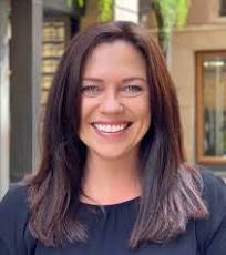 Suzie Tombs, copywriter, in a black top standing in front of a building.