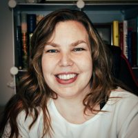A woman smiling in front of a book shelf.